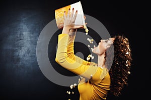 Sideview of beautiful woman pouring cheesy popcorn from bucket