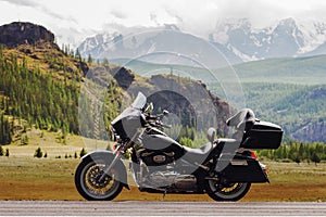 Sideview of black motorcycle touring on a background of mountains range in the snow