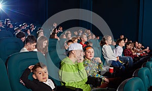 Sideview of boys watching movie in the cinema.