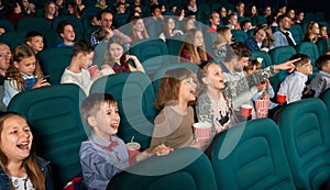 Sideview of funny children watching movie in the cinema.