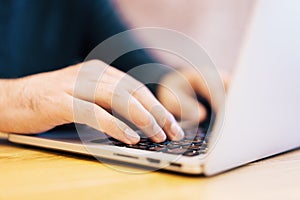 Sideview of man using laptop on desktop