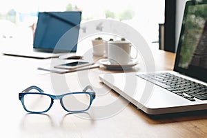 Sideview of office desk with laptop, glasses and other items