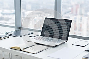 Sideview of office desktop with blank laptop and various tools.