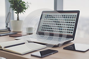 Sideview of office desktop with blank laptop and various tools.