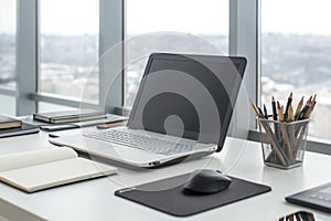 Sideview of office desktop with blank laptop and various tools. photo