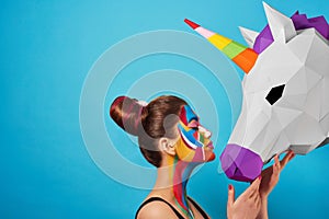 Sideview of pop art portrait of model wearing colorful figures on her face.