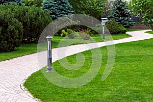 Sidewalk in the backyard of the mansion with green lawns.