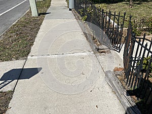 A sidewalk and black metal fence summer