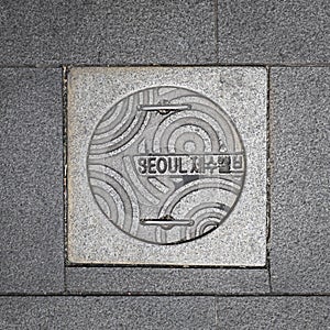 Sidewalk concrete manhole cover in downtown Seoul.