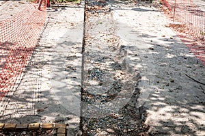 Sidewalk construction site for repair of the asphalt footpath surrounded and protected with orange safety net or fence