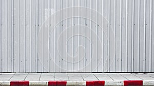 Sidewalk and curb red-white with metal corrugated wall