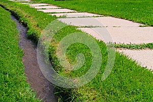 Sidewalk and ditch in grass photo