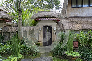 The sidewalk leads to a enter in house with Balinese sculptures in a tropical garden, island Bali, Indonesia
