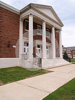 Sidewalk by an old brick high school with columns