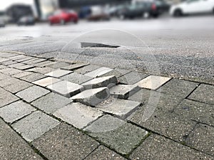 Sidewalk pavement tiles for pedestrians are uneven due to lack of maintenance
