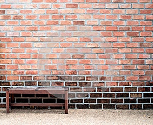 Sidewalk scene with wooden bench and red brick wall