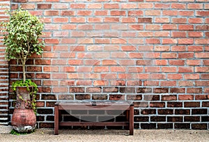 Sidewalk scene with wooden bench and red brick wall