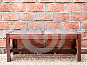 Sidewalk scene with wooden bench and red brick wall