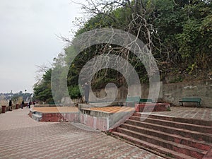 sidewalk way lined by trees and benches for relaxing along the coastline of Chenab river Akhnoor