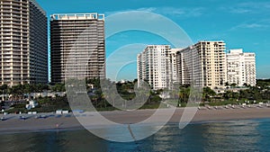 sideways aerial footage of hotels and luxury condominiums surrounded by lush green palm trees and plants with blue sky