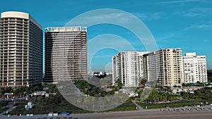 sideways aerial footage of hotels and luxury condominiums surrounded by lush green palm trees and plants with blue sky