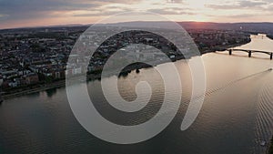 Sideways move of a drone showing Mainz with the Rhine river with cargo ships and reflections on the water and old bridge in