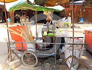 Street vendor is squeezing sugar cane juice