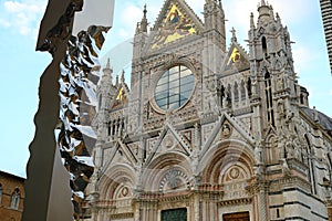 Siena Cathedral and sculpture by Helidon Xhixha. Facade Made with white and colored marble and stainless steel sculpture
