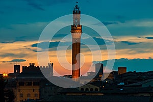 Siena cityscape at dusk with famous Torre del Mangia. Tuscany, Italy.