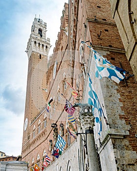 Siena, Italy - The flags of the districts displayed on the facade of the public building