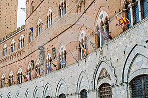 Siena, Italy - The flags of the districts displayed on the facade of the public building