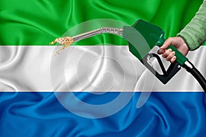 SIERRA LEONE flag Close-up shot on waving background texture with Fuel pump nozzle in hand. The concept of design solutions. 3d