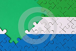 Sierra Leone flag is depicted on a completed jigsaw puzzle with free green copy space on the left side