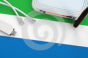 Sierra Leone flag depicted on table with internet rj45 cable, wireless usb wifi adapter and router. Internet connection concept