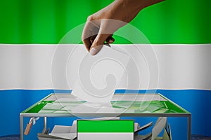 Sierra Leone flag, hand dropping ballot card into a box - voting, election concept