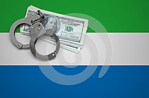 Sierra Leone flag with handcuffs and a bundle of dollars. The concept of breaking the law and thieves crimes