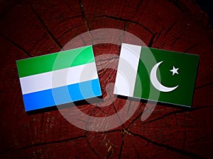 Sierra Leone flag with Pakistan flag on a tree stump isolated