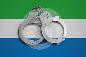 Sierra Leone flag and police handcuffs. The concept of observance of the law in the country and protection from crime