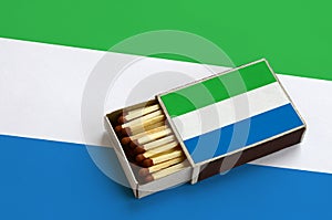 Sierra Leone flag is shown in an open matchbox, which is filled with matches and lies on a large flag