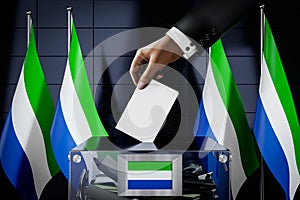 Sierra Leone flags, hand dropping ballot card into a box - voting, election concept