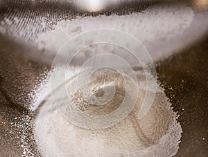 Sieving baking soda powder into a bowl.