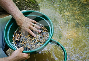 Sift and classify mineral rich soil with gold panning classifier pan. photo