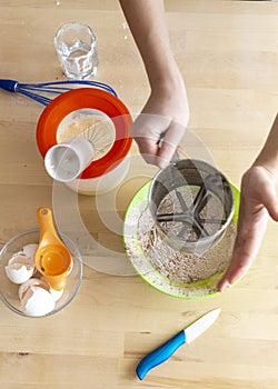 Sift flour through a sieve. Cooking a dessert. The ingredients on the table, flour, sugar, kitchen scales, eggs, mixer.