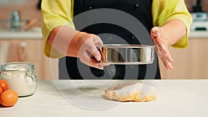 Sifting flour on dough using metallic sieve