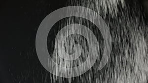 Sifting flour through sieve. Black background. Slow motion.