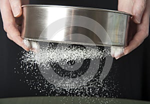 Sifting flour through a sieve closeup