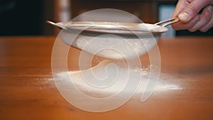 Sifting Flour Through Sieve on a Wooden Table in a Home Kitchen. Slow Motion