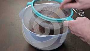 Sifting a mixture of white flour, sugar and cocoa powder. Male hand.