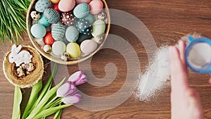 Sifting powder sugar over bunny shaped ester cookie on decorated wooden table. Easter holiday decorations, Easter concept