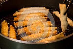 Sigara Boregi / Turkish Cigar Shaped Rolls frying in a pan.